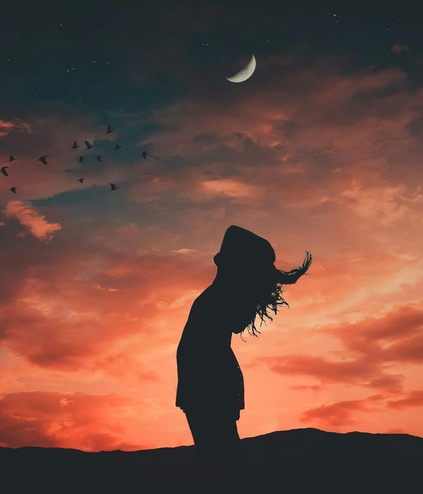 Person stretching outdoors during a sunrise, silhouette against a colorful sky.