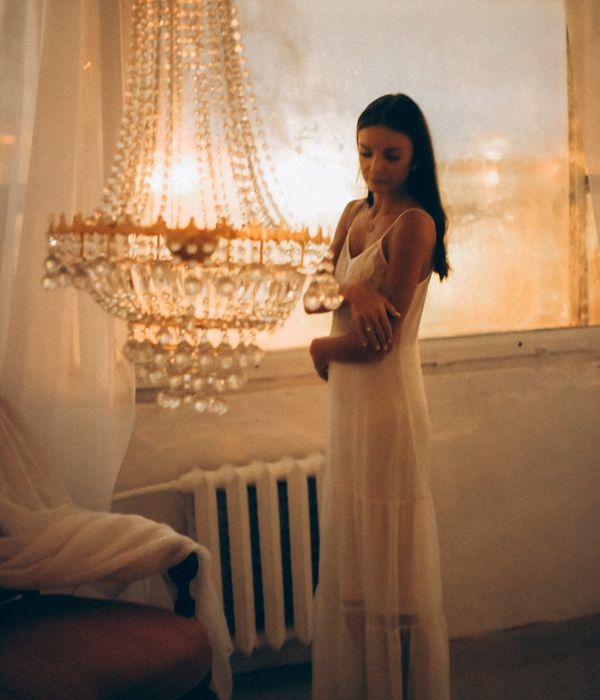 Woman in a calm, focused pose in a room with warm lighting.